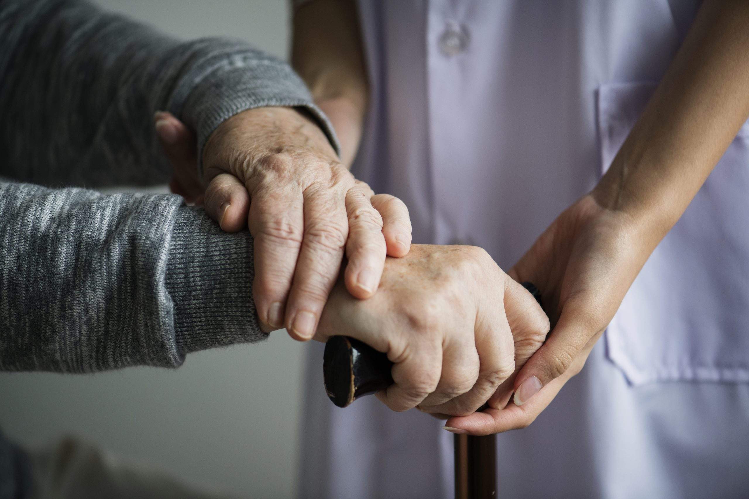 Care home nurse holding hands with elderly patient