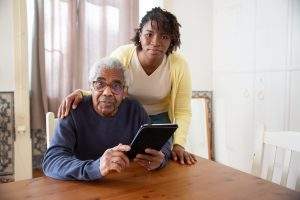Woman helping elderly man with tablet